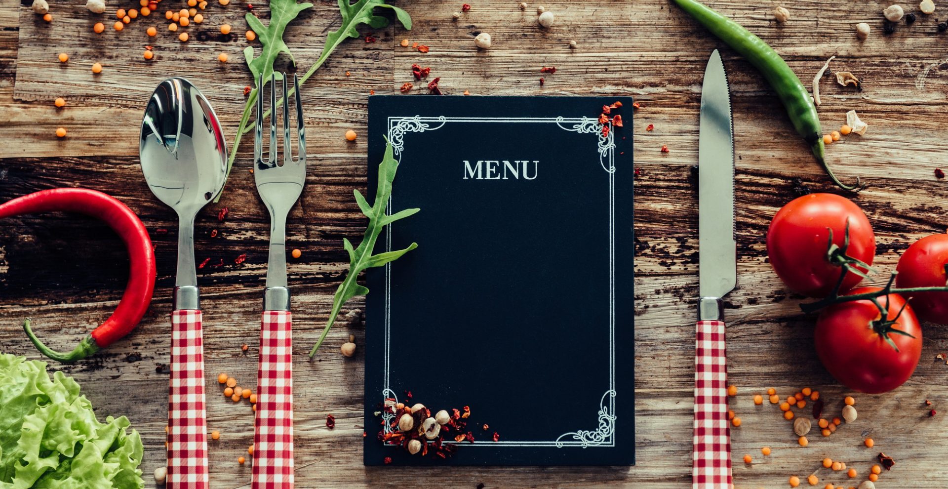 Restaurant menu. Top view of chalkboard menu laying on the rustic wooden desk with vegetables around